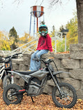 Child on a dirt bike with a helmet, sitting on a stone wall outdoors. Side view of a blue youth electric dirt bike parked outdoors. Valtinsu EM5